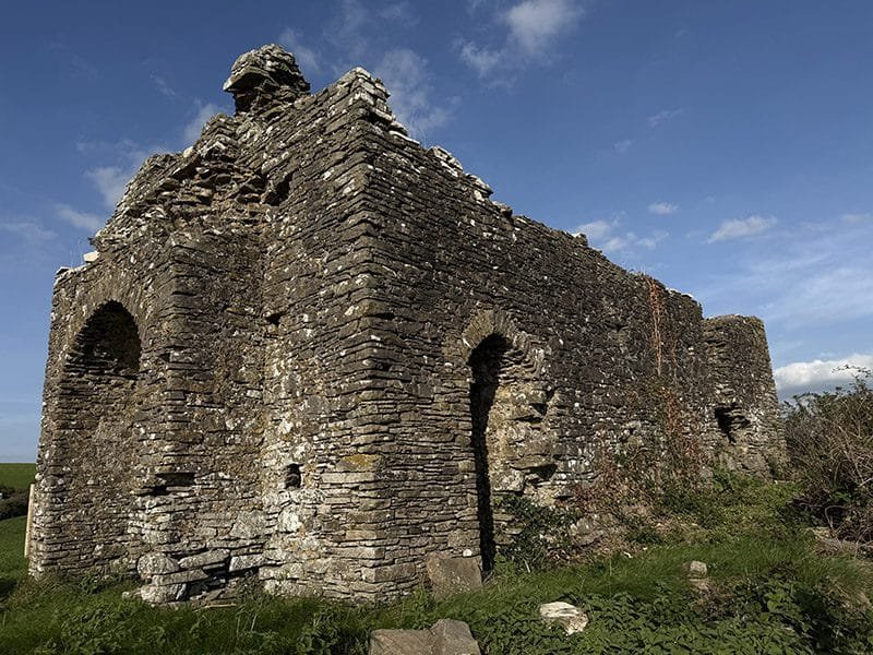 ruined chapel without roof or doors on the top of a hill